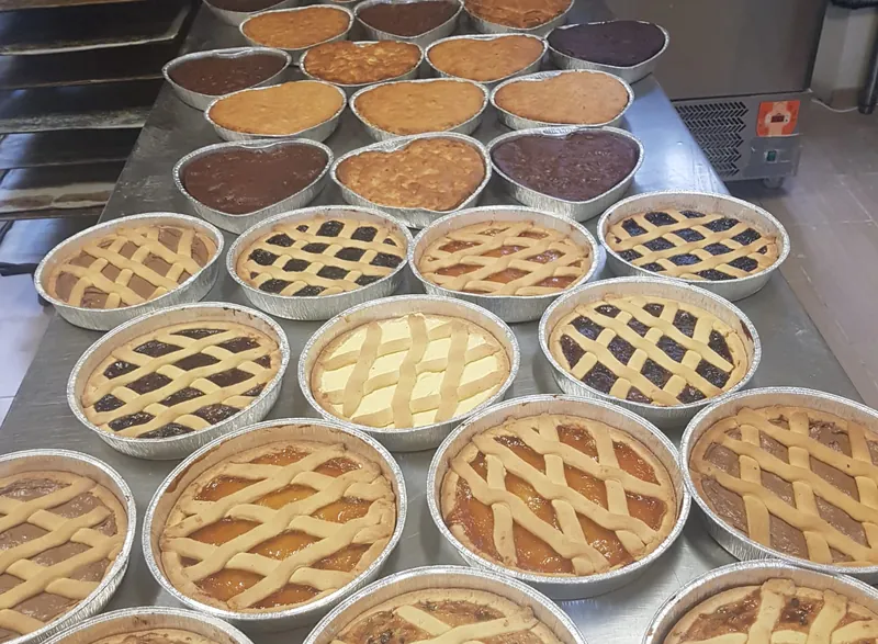 Crostate con la grata e torte a cuore sul tavolo del laboratorio